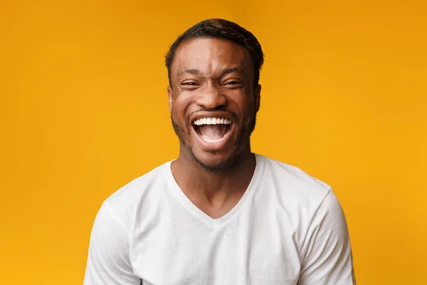 Africano americano homem rindo olhando para a câmera sobre fundo amarelo — Fotografia de Stock