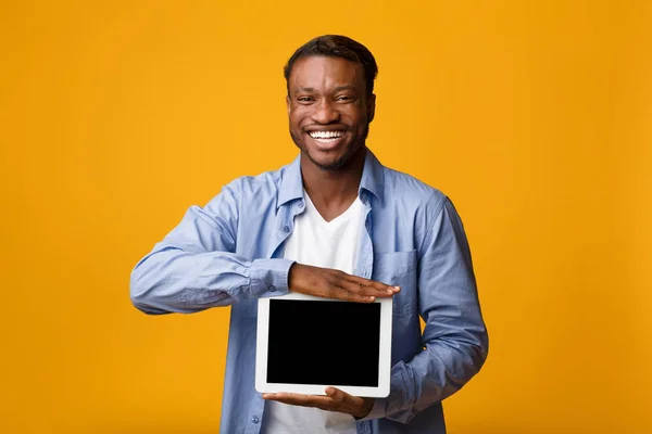 Sonriente hombre afroamericano mostrando la pantalla de la tableta en el estudio, burla — Foto de Stock