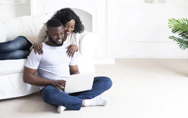 Familia africana joven usando el ordenador portátil en casa, planeando vacaciones juntos —  Fotos de Stock