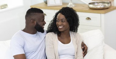 gülümseyen çift kanepede oturan ve birbirlerine bakarak