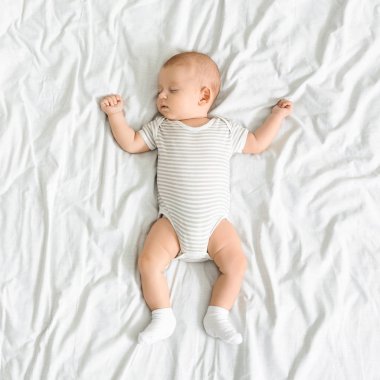 Sevimli yenidoğan bebek kolları ile yatakta uyuklama