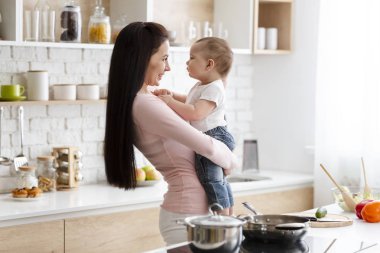 Mutlu kadın mutfakta onun bebek oğlu ile kucaklayan