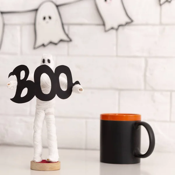 Biały Duch postać trzyma słowo Boo w pobliżu czarnego filiżanki z herbatą — Zdjęcie stockowe