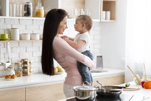 Glückliche Frau umarmt ihren kleinen Sohn in der Küche — Stockfoto
