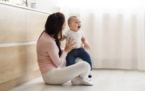 Sevimli bebek anne ile oynarken, mutfakta katta oturan — Stok fotoğraf