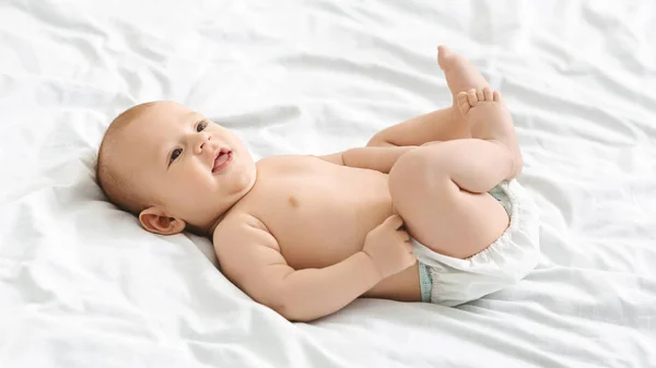 Evde yatakta yatan bebek bezi komik küçük bebek — Stok fotoğraf