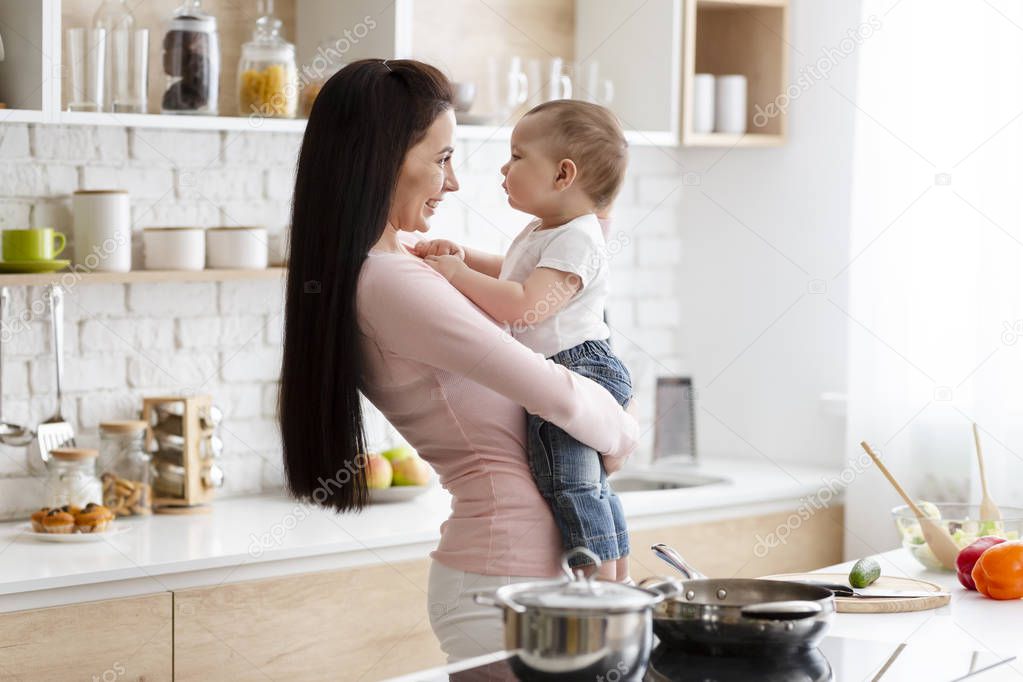 Happy woman embracing with her baby son at kitchen