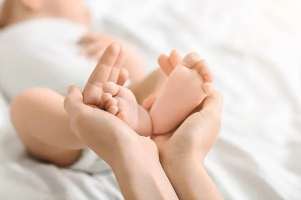 手に彼女の生まれたばかりの赤ちゃんの小さな足を保持している母 — ストック写真