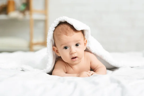 Retrato de menino recém-nascido bonito espreitando debaixo do cobertor — Fotografia de Stock