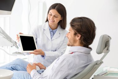 Female dentist doctor showing patient blank digital tablet screen