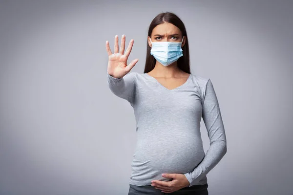 Zwangere meisje in medische gezichtsmasker Gesturing stop, Studio schot — Stockfoto