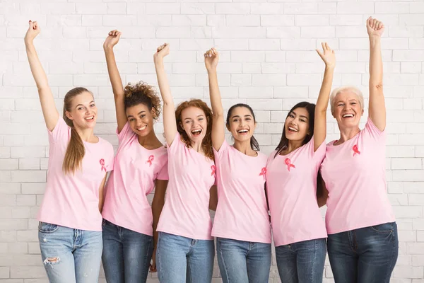 Felice signore in seno cancro T-shirt alzando le mani in piedi al coperto — Foto Stock