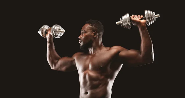 Afrikanischer Bodybuilder trainiert, schiebt Hanteln in die Höhe — Stockfoto