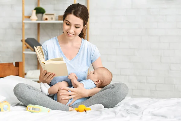 Genç anne bebek bebeğine kitap okuyor — Stok fotoğraf