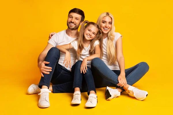 Genitori e piccola figlia seduti e abbracciati sul pavimento, Studio — Foto Stock