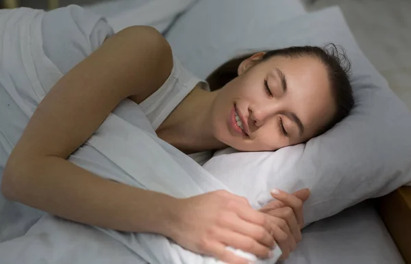 Lány alszik az ágyban, reggel Napsugár hullanak az arcon — Stock Fotó