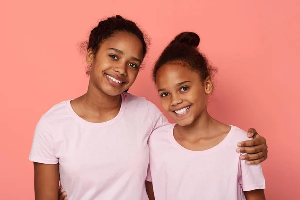 Hermanitas lindas abrazando sobre fondo rosa — Foto de Stock