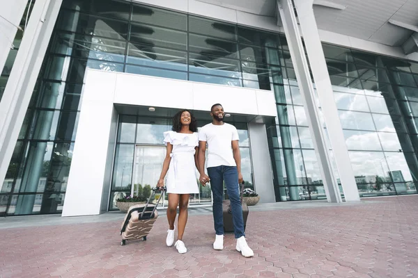 Feliz pareja negra millennial disfrutando de un nuevo destino en el edificio del aeropuerto —  Fotos de Stock