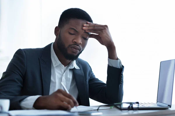 Serieuze Afro zakenman vullen papierwerk op Workplace in modern kantoor — Stockfoto