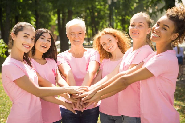 T-shirts pour femmes atteintes du cancer du sein tenant la main debout dans le parc — Photo