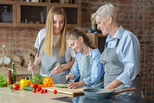 Volwassen dames onderwijzen meisje hoe te koken — Stockfoto