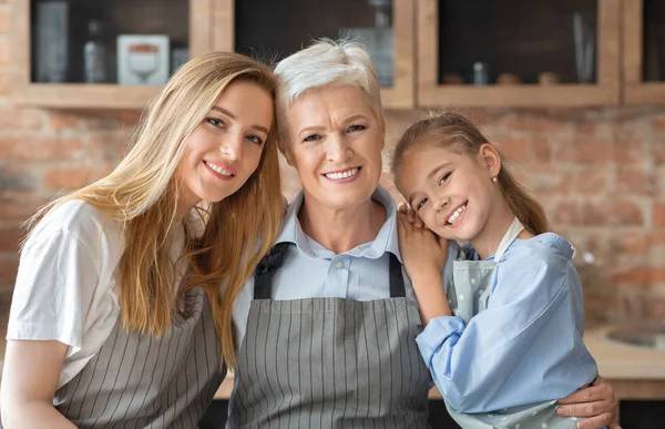 Retrato de madre, hija y abuela abrazándose en la cocina — Foto de Stock