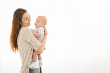 Young happy woman holding her newborn sweet baby and smiling