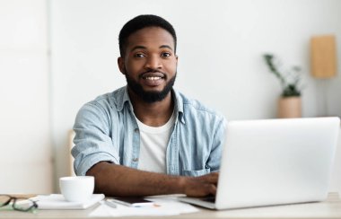 Portrait of handsome african american employee using laptop at workplace