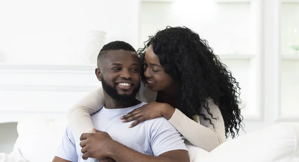 Jong zwart man en vrouw omarmen op bank thuis — Stockfoto