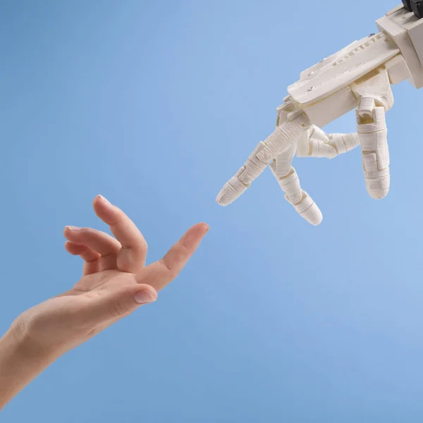 青い背景の上に女性とロボットの手が互いに手を差し伸べている — ストック写真