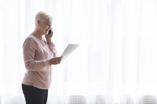 Seniorin hält Papiere und telefoniert mit Kunden — Stockfoto
