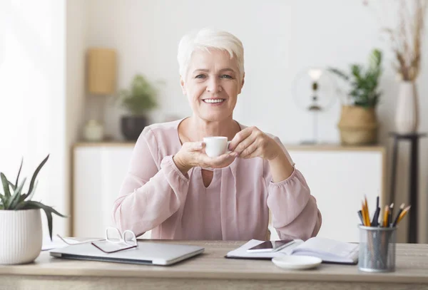 Vreedzame oude dame met koffiepauze tijdens het werk — Stockfoto