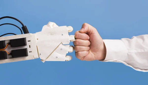 Робот и человеческая рука делают жест удара кулаком — стоковое фото