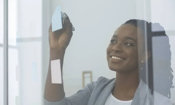 Empresaria leyendo notas coloridas en tablero de cristal en la oficina — Foto de Stock