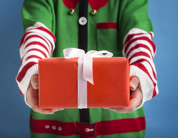 Santas pequeño ayudante celebración de regalo de vacaciones con cinta en el fondo —  Fotos de Stock