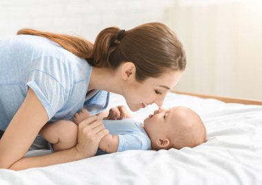 Genç ve güzel anne yeni doğmuş sevimli oğluyla burun buruna dokunuyor.