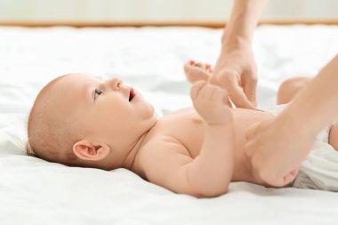 Anne, sevimli bebeğine bebek bezi bağlıyor.