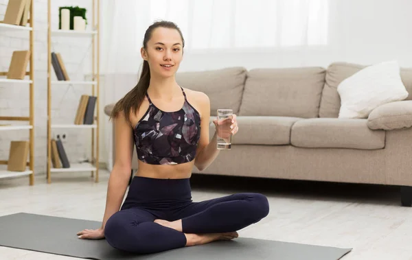 Fit girl sitting in lotus pose and drinking pure water — Stock Photo, Image