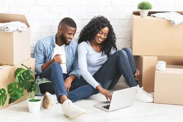Cheerful couple sitting on floor at new apartment, using laptop — Stock Photo, Image
