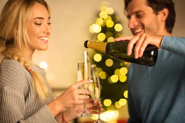 Hombre vertiendo champán en las copas, celebrando la Navidad con su esposa — Foto de Stock