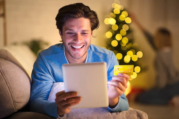 Handsome man shopping online on tablet on New Years eve — ストック写真