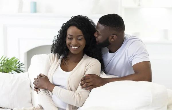 Handsome black guy whispering something to his girlfriends ear — Stockfoto