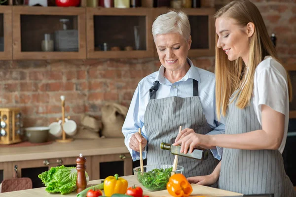 Junge Frau fügt Olivenöl zu gesundem Gemüsesalat hinzu — Stockfoto