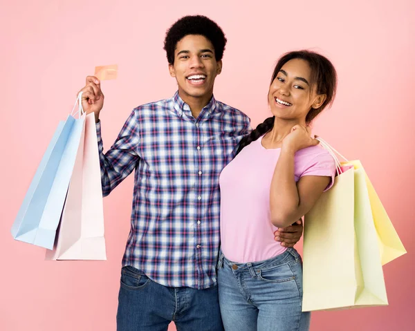 Glückliche Teenager mit Einkaufstüten vor rosa Hintergrund — Stockfoto