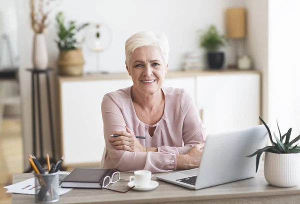 Glimlachende senior zakenvrouw werken met laptop thuis — Stockfoto