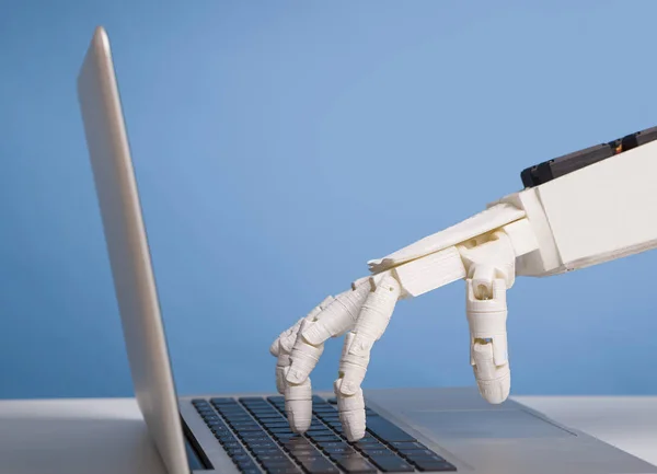 Robotic hand typing on laptop keyboard, free space — ストック写真