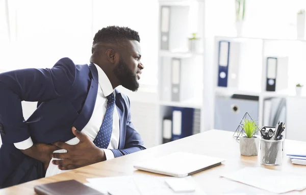 Afrikaanse jonge zakenman houdt zijn kant, lijdt aan leverpijn — Stockfoto