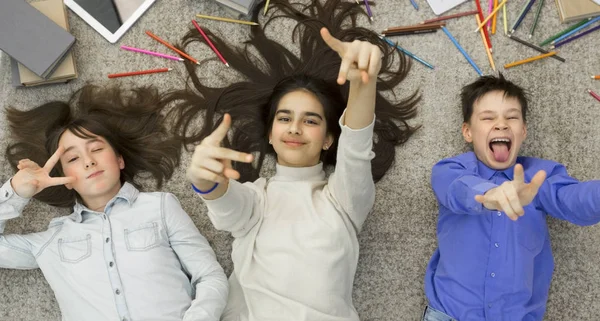 Alegre niños engañando, acostado en la alfombra y divertirse — Foto de Stock