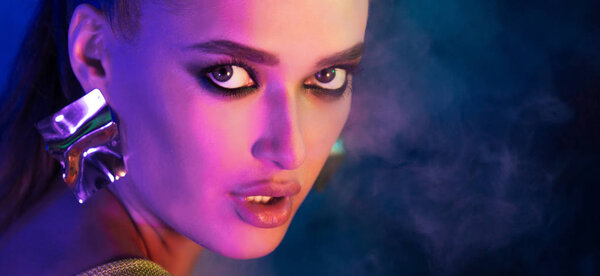 Portrait of woman in neon blue smoke