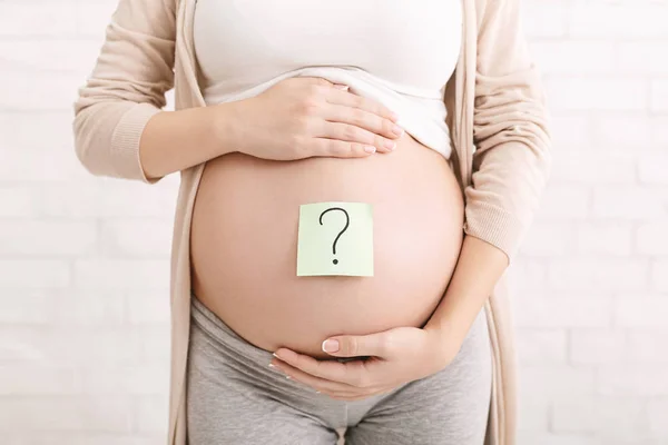 Беременная женщина с вопросительным знаком на бумажных наклейках — стоковое фото